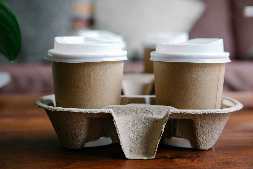 Close-up of eco-friendly disposable coffee cups in a cardboard holder, perfect for takeout or delivery.