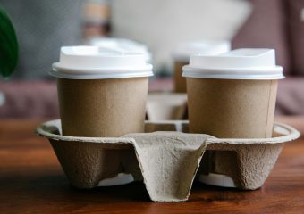 Close-up of eco-friendly disposable coffee cups in a cardboard holder, perfect for takeout or delivery.