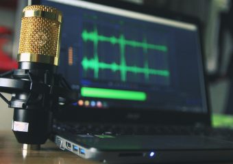 Close-up of a golden microphone and laptop used for audio editing.