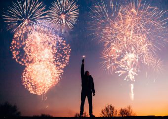 A person celebrates under vibrant fireworks in the evening sky in Kragujevac, Serbia.