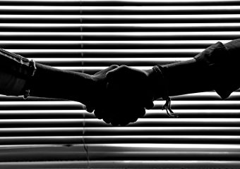 Silhouette of two people shaking hands symbolizing partnership and trust.